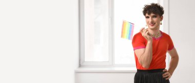 Evinin penceresinin yanında LGBT bayrağı taşıyan genç bir transseksüel kadın. Tasarım için pankart