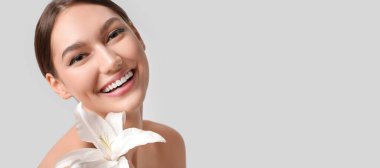 Açık arkaplanda zambak çiçeği olan genç ve güzel bir kadın.