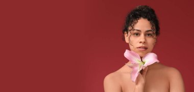Kırmızı arka planda zambak çiçeği olan güzel, Afro-Amerikalı bir kadın.