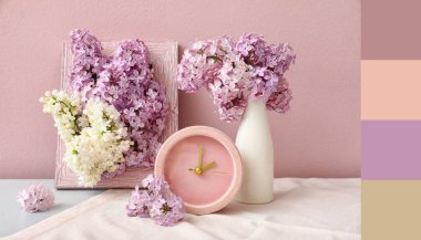 Pembe duvarın yanındaki beyaz masada çerçeveli ve saati olan güzel kokulu leylak çiçekleri vazosu. Farklı renk desenleri