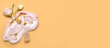 Yüz masajı silindiri, gül esaslı yağ ve bej arka planda uyku maskesi metin için yer var