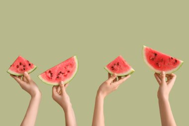 Yeşil arka planda olgun karpuz dilimleriyle kadın elleri.