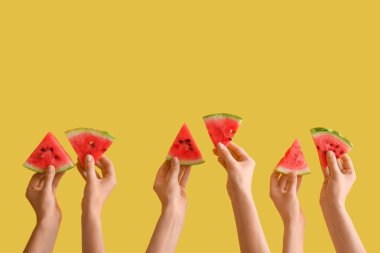 Sarı arka planda olgun karpuz dilimleriyle kadın elleri.