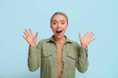 Mavi arka planda şaşırmış genç bir kadın.