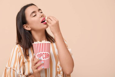 Bej arka planda patlamış mısırla güzel, genç bir kadın.