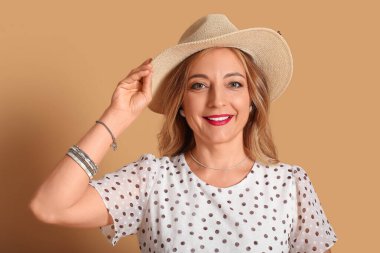 Kahverengi arka planda şık aksesuarları olan güzel olgun bir kadın.