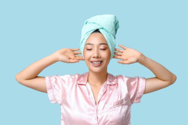 Mavi arka planda duş aldıktan sonra genç Asyalı kadın