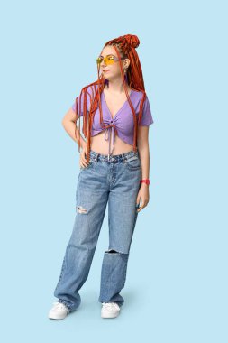 Mavi arka planda rastaları olan zarif genç bir kadının portresi.