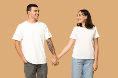 Bej arka planda el ele tutuşup gülümseyen genç bir çift.