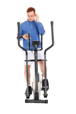 Sportif genç adam beyaz arka planda bisiklet egzersizi yaparken müzik dinliyor.