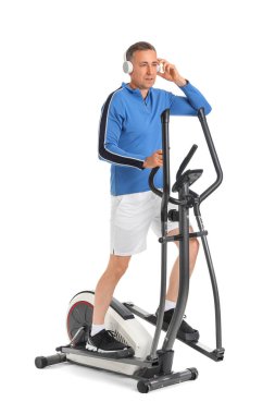 Beyaz arka planda egzersiz yapan kulaklıklı, sportif, olgun bir adam.