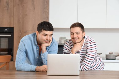 Mutfakta dizüstü bilgisayarı olan yakışıklı kardeşler.