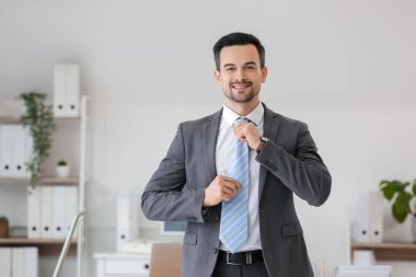 Yakışıklı iş adamı ofiste kravat takıyor.