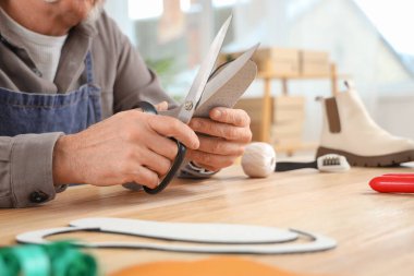 Erkek ayakkabıcı atölyede taban kesiyor, yakın plan.