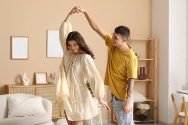 Güzel, genç bir çift oturma odasında dans ediyor.