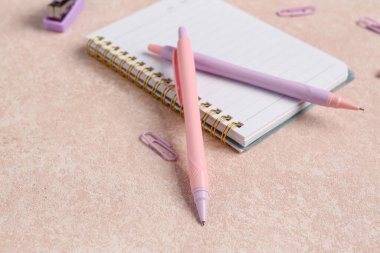 Bej grunge masasında not defteri ve okul kağıdı olan kalemler.