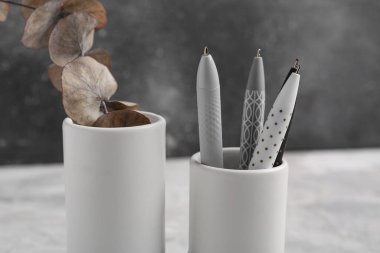 Okaliptüs dallı vazo ve gri grunge masasında kalemler.