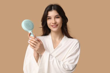 Kahverengi arka planda mavi saç fırçası olan güzel bir genç kadın.