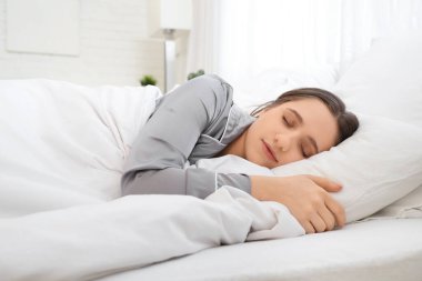Yatak odasında battaniyeyle uyuyan genç kadın.