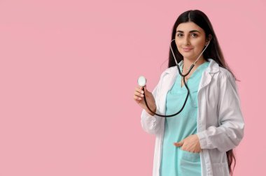 Pembe arka planda steteskobu olan güzel bir bayan doktor.