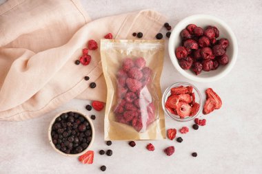 Composition with tasty freeze-dried berries on light background clipart