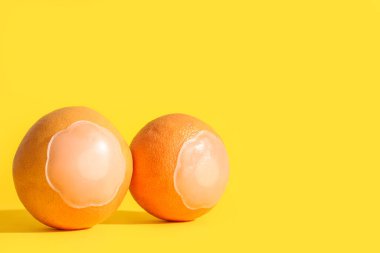 Sarı arka planda silikon meme uçları olan taze greyfurtlar. Erotik ve kadın sağlık hizmetleri kavramı