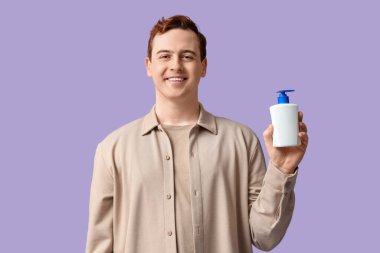 Leylak arkaplanı dezenfektanı olan genç bir adam.