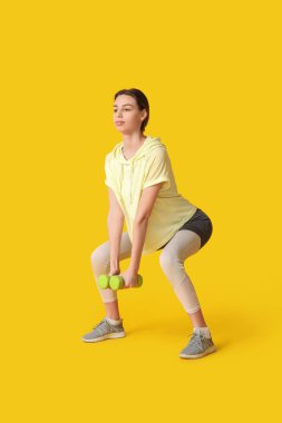 Sarı arka planda çalışan güzel, genç, mutlu, sportif bir kadın.