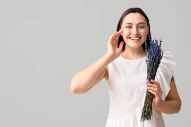 Güzel, mutlu, genç bir kadın ve açık arkaplanda bir demet lavanta çiçeği.