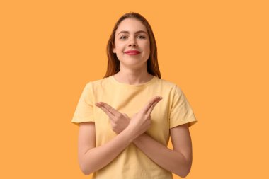 Young deaf mute woman using sign language on orange background