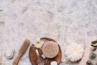 Ahşap tepsi, banyo süngeri, masaj vücut fırçası, havlu, deniz tuzu ve grunge arkaplanındaki plumeria çiçeği karışımı.