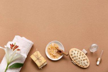 Banyo malzemeleri, bir şişe serum ve kahverengi arka planda zambak çiçeği karışımı.