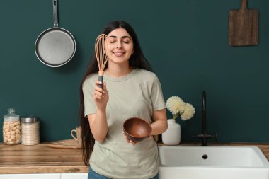 Modern mutfakta çırpı ve kase ile güzel genç bir kadın.