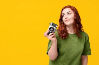 Sarı arka planda kamera olan güzel kızıl saçlı kadın.