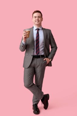 Pembe arka planda bir fincan taze kahve ile yakışıklı bir genç.