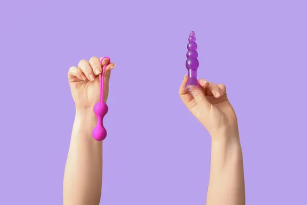 stock image Female hands with sex toys on lilac background, closeup