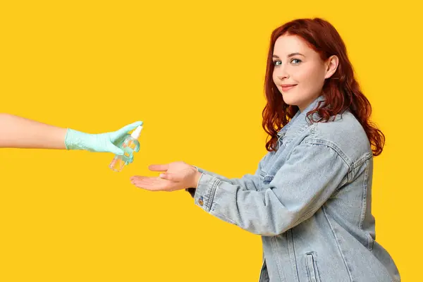 stock image Beautiful young happy woman and hand with bottle of sanitizer on yellow background