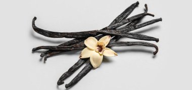 Aromatik vanilya çubukları ve açık arkaplanda çiçek