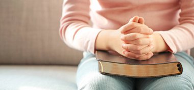 İncil 'i olan şirin küçük bir kız evde dua ediyor, yakın plan. Tasarım için pankart