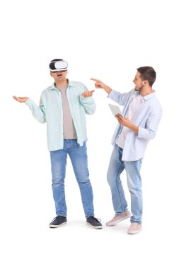 Beyaz arka planda VR gözlüğü kullanan yakışıklı genç kardeşler.