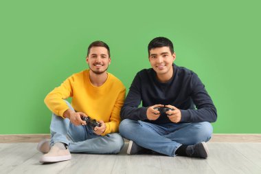 Yeşil arka planda video oyunu oynayan küçük kardeşler