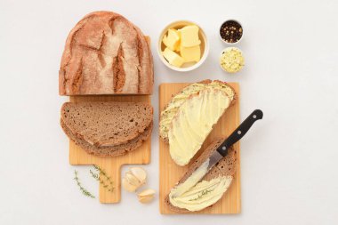 Tahta tahtalar taze tereyağlı, sarımsaklı ve biberli ekmek dilimleri beyaz arka planda.