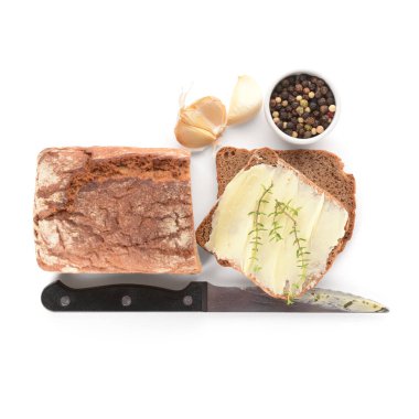 Taze tereyağlı ekmek dilimleri, sarımsak ve beyaz arka planda bir kase biber.