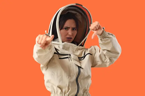 stock image Female beekeeper with dislike pointing at viewer on orange background