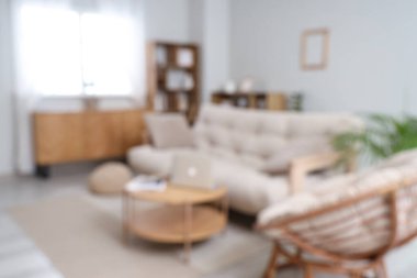 Kanepesi ve kahve masası olan, bulanık manzaralı, aydınlık oturma odasının şık bir iç mekanı.