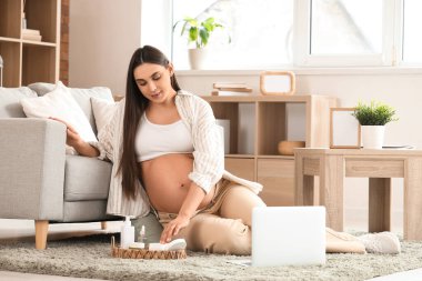 Krema kavanozuyla evde oturan hamile bir kadın.