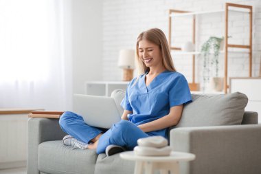 Oturma odasındaki kanepede dizüstü bilgisayarı olan kadın stajyer.