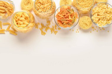 Hafif arka planda cam kaselerde farklı pişirilmemiş makarna kompozisyonu