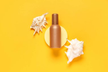 Composition with bottle of sunscreen cream and seashells on orange background clipart