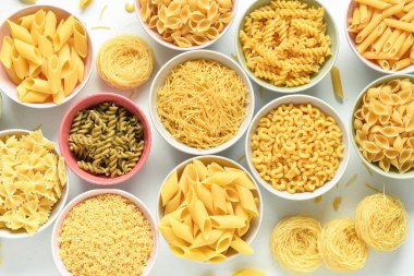 Beyaz arka planda farklı çiğ makarnalar.